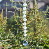 Handmade suncatcher with frosted aqua recycled glass beads and clear crystal prism, hanging outdoors in sunlight.