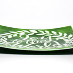 A square green glass serving tray with a white design of a wreath and the words &#39;Joy to the World&#39;. Viewed from the side with tray flat on white background.