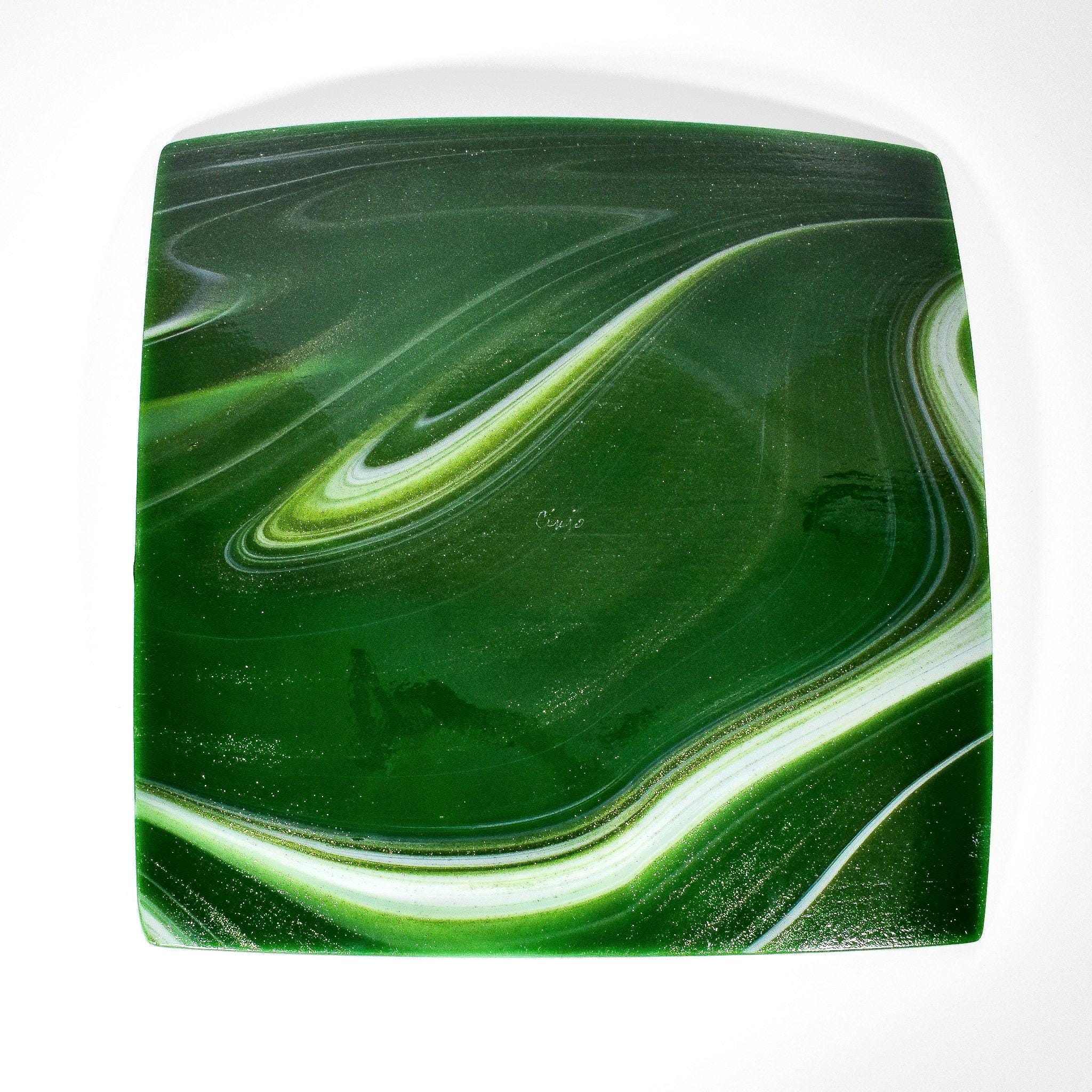 Backside of a square green glass plate showing white swirl design on sparkly aventurine green glass. The plate has a glossy finish and a subtle sparkle. On white background.