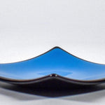 Square fused glass dish with solid blue center, black trim and black base, sitting white surface.