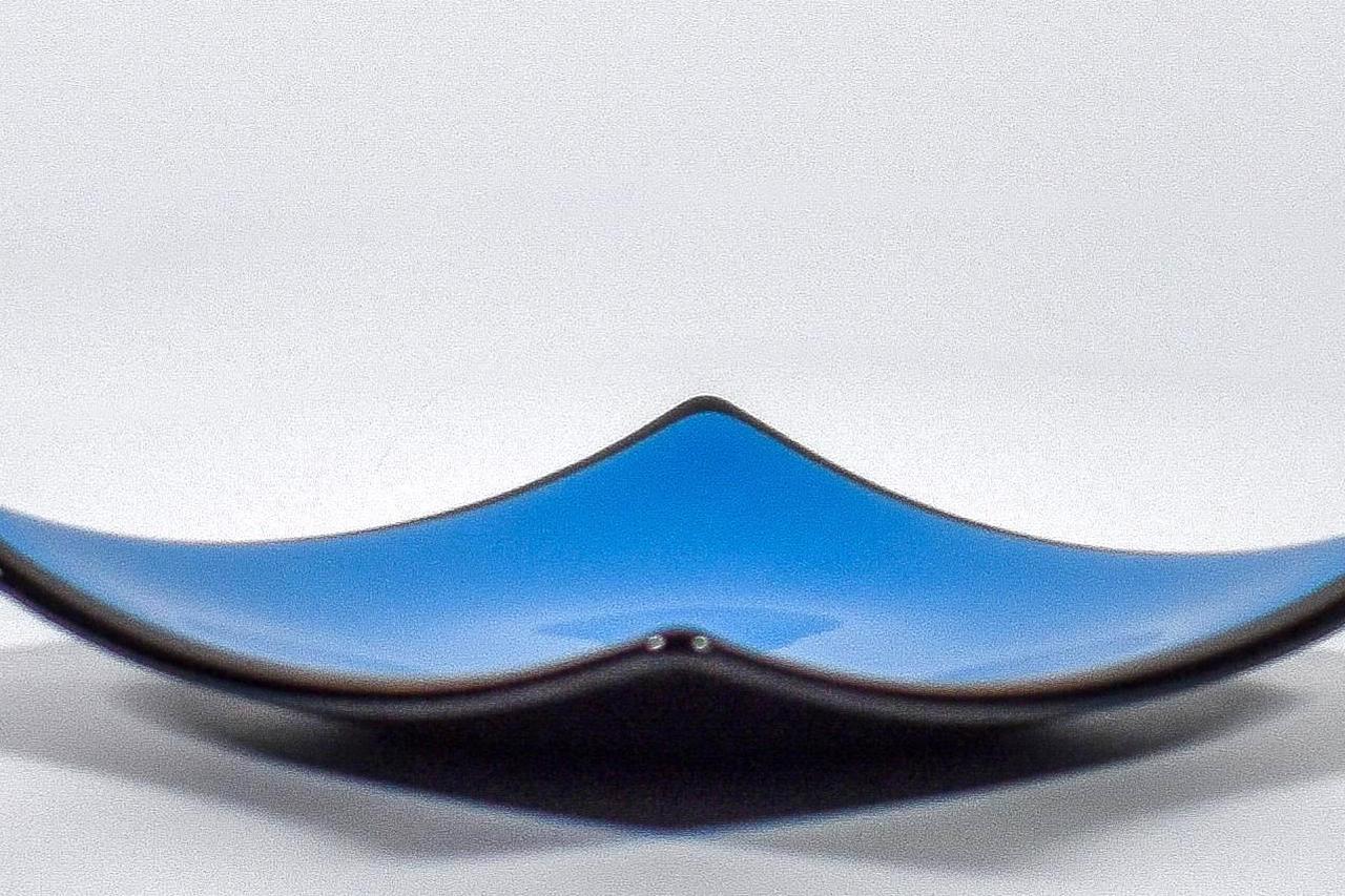 Square fused glass dish with solid blue center, black trim and black base, sitting white surface.