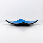 Square fused glass dish with solid blue center, black trim and black base, sitting white surface.