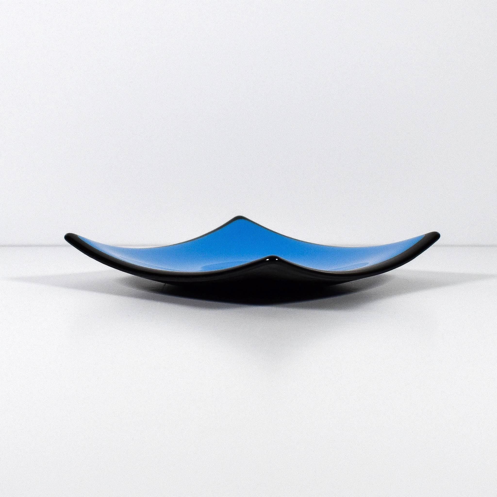 Square fused glass dish with solid blue center, black trim and black base, sitting white surface.