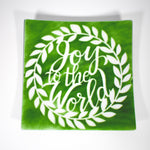 Large square fused glass platter with &quot;Joy to the World&quot; design in green with white, against white background.