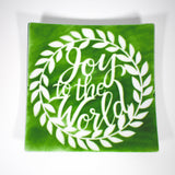 Large square fused glass platter with &quot;Joy to the World&quot; design in green with white, against white background.