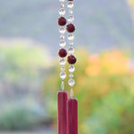 Large cranberry red jade stones beaded with glass and crystals, anchored by two pieces of dark cranberry pink fused glass, hanging vertically.