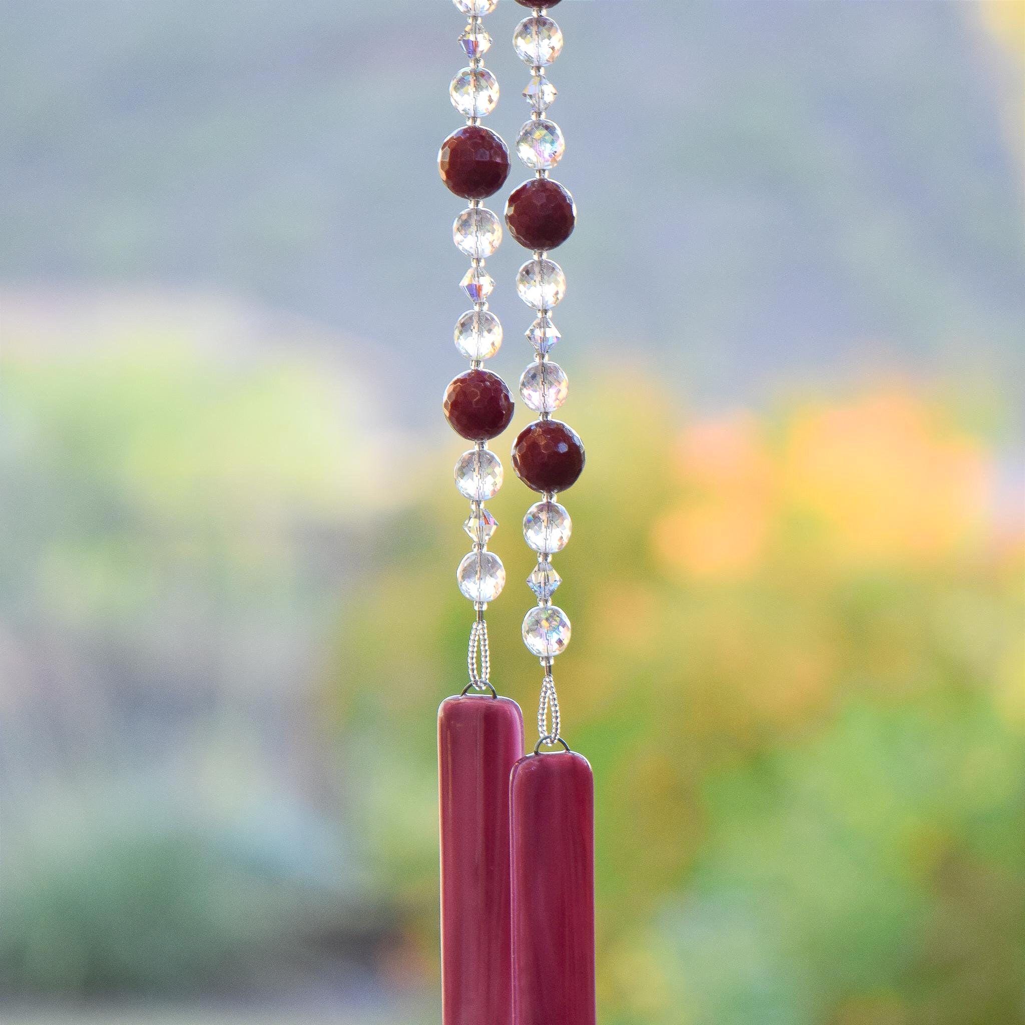 Large cranberry red jade stones beaded with glass and crystals, anchored by two pieces of dark cranberry pink fused glass, hanging vertically.