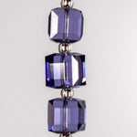 Three cube-shaped purple beads with silver-lined seed bead spacers in between. Hanging vertically against white background.