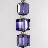 Three cube-shaped purple beads with silver-lined seed bead spacers in between. Hanging vertically against white background.