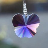 A purple crystal butterfly charm hanging from a wire lined with silver-lined seed beads.