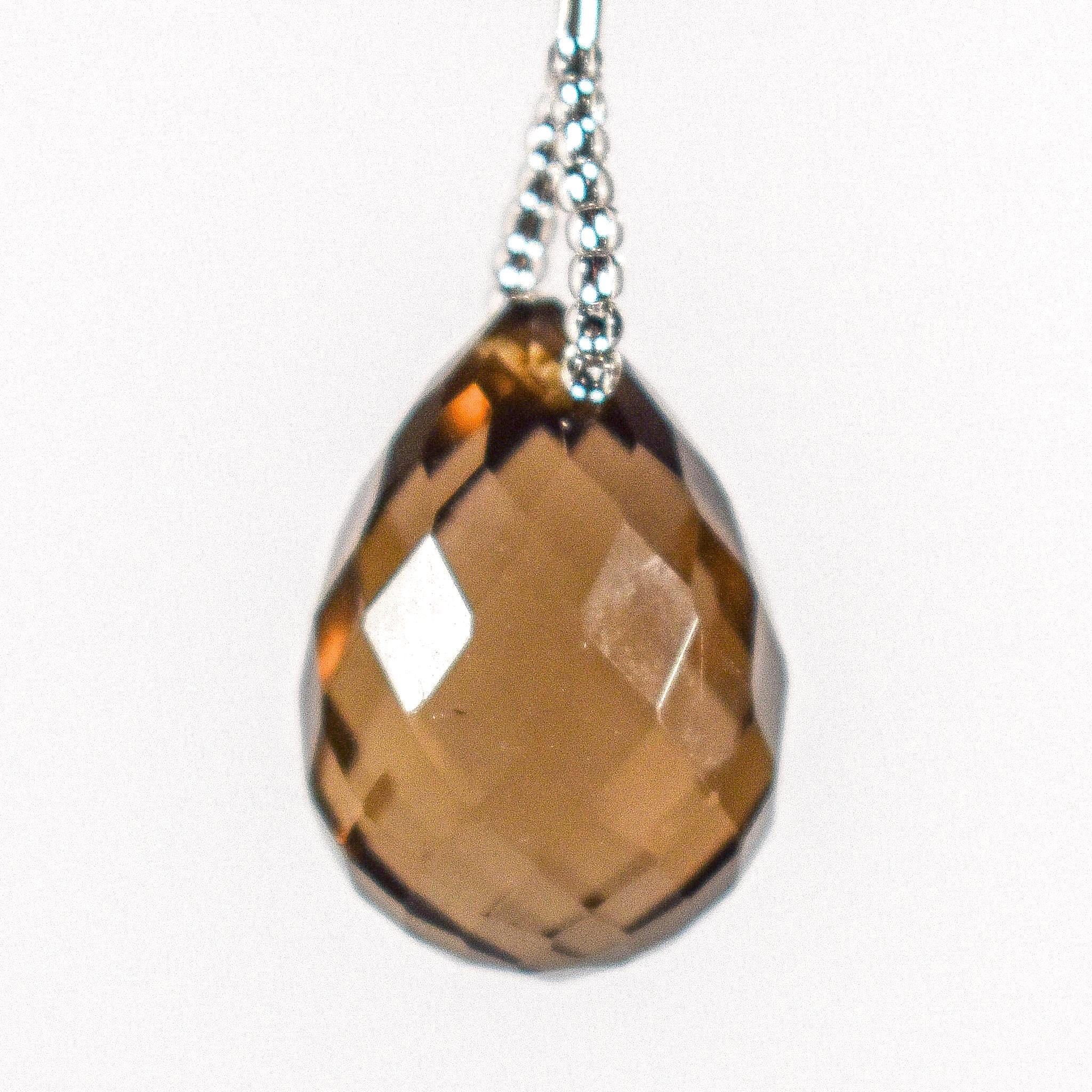 A faceted, teardrop shaped brown smoky quartz stone pendant hanging from a wire covered in silver-lined seed beads.
