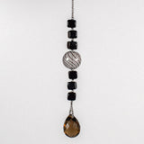 Small sun catcher hanging vertically in front of white background, made with six Murano glass cube beads flanking a large, round swirly bead and anchored by a large smoky quartz pendant.