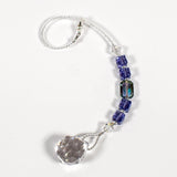 Small sun catcher coiled on a white surface, made with purple crystal cube beads, a large emerald cut crystal and a round crystal prism anchor.