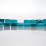 A rectangular glass tray with a mosaic tile design. The tray features a pattern of square tiles in shades of teal and white. The tiles are arranged in a grid-like pattern, creating a visually appealing surface. The tray is placed on a white surface. View is from the long side.