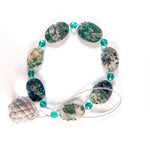 21&quot; long sun catcher made of large oval azurite malachite stone beads paired with small turquoise glass beads and a large crystal prism. This photo shows the sun catcher coiled on a white surface.