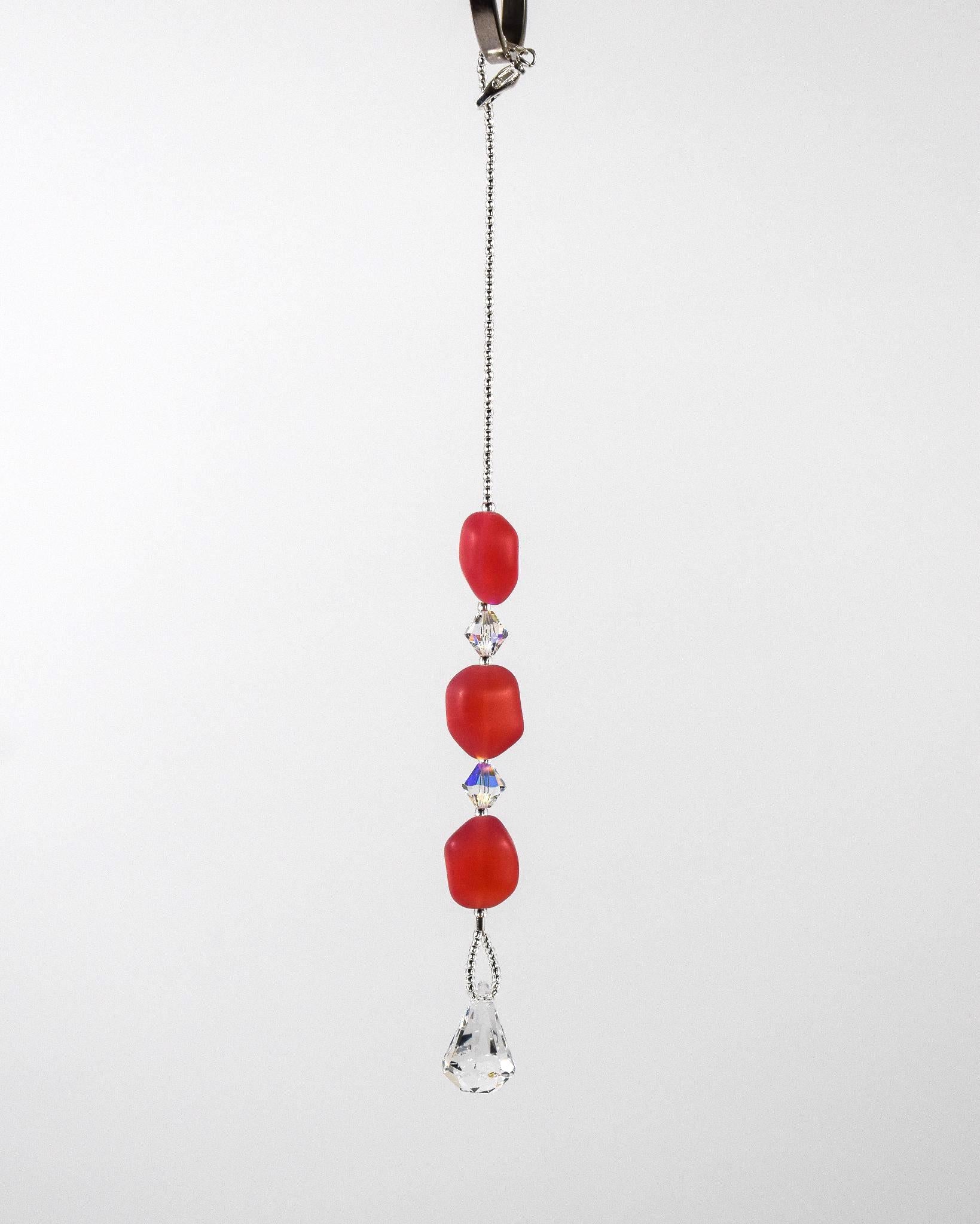 Pink beaded car rearview mirror charm.  The charm features three pink beads interspersed with clear crystal accents and a dangling clear crystal teardrop. The beads are irregular in shape and made of glass.  White background. A silver-lined clasp is used at the top to wrap extra wire around a hook.