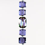 A strand of iridescent purple crystal beads with a clear crystal bead in the center. White background.