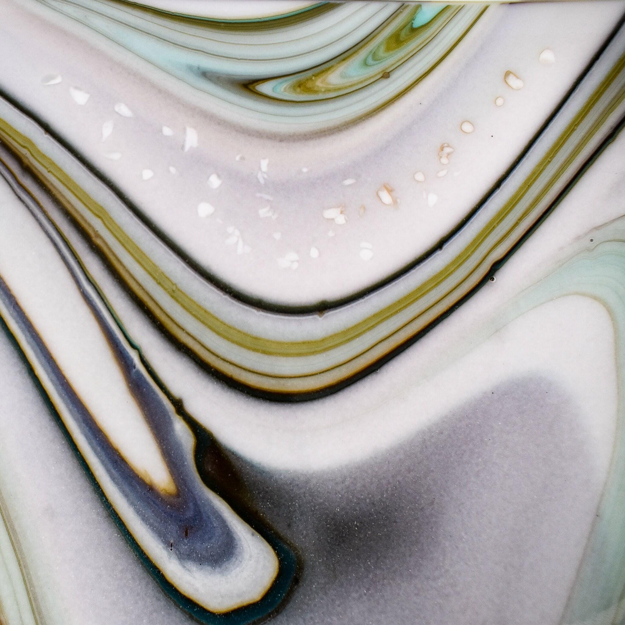 Close up view of abstract background with swirling patterns in shades of white, gray, green, and brown.