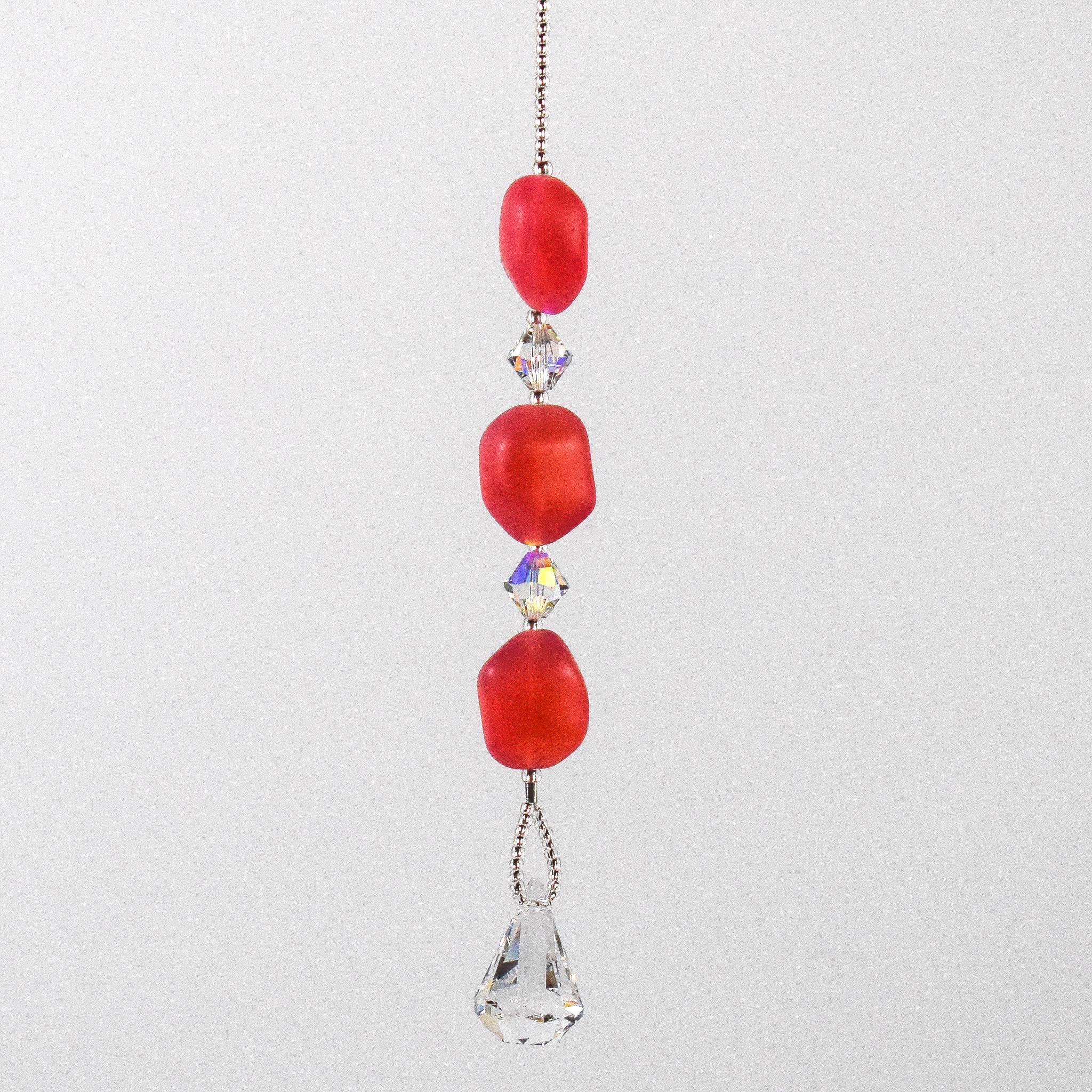 Pink beaded car rearview mirror charm.  The charm features three pink beads interspersed with clear crystal accents and a dangling clear crystal teardrop. The beads are irregular in shape and made of glass.  White background.