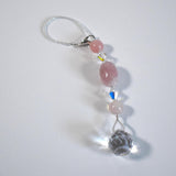Large oval rose quartz bead flanked by Austrian crystal and two smaller round rose quartz beads, placed on a white background.
