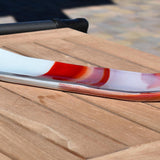 Long fused glass channel tray outdoors on a wood table, white with red, orange and pink design.