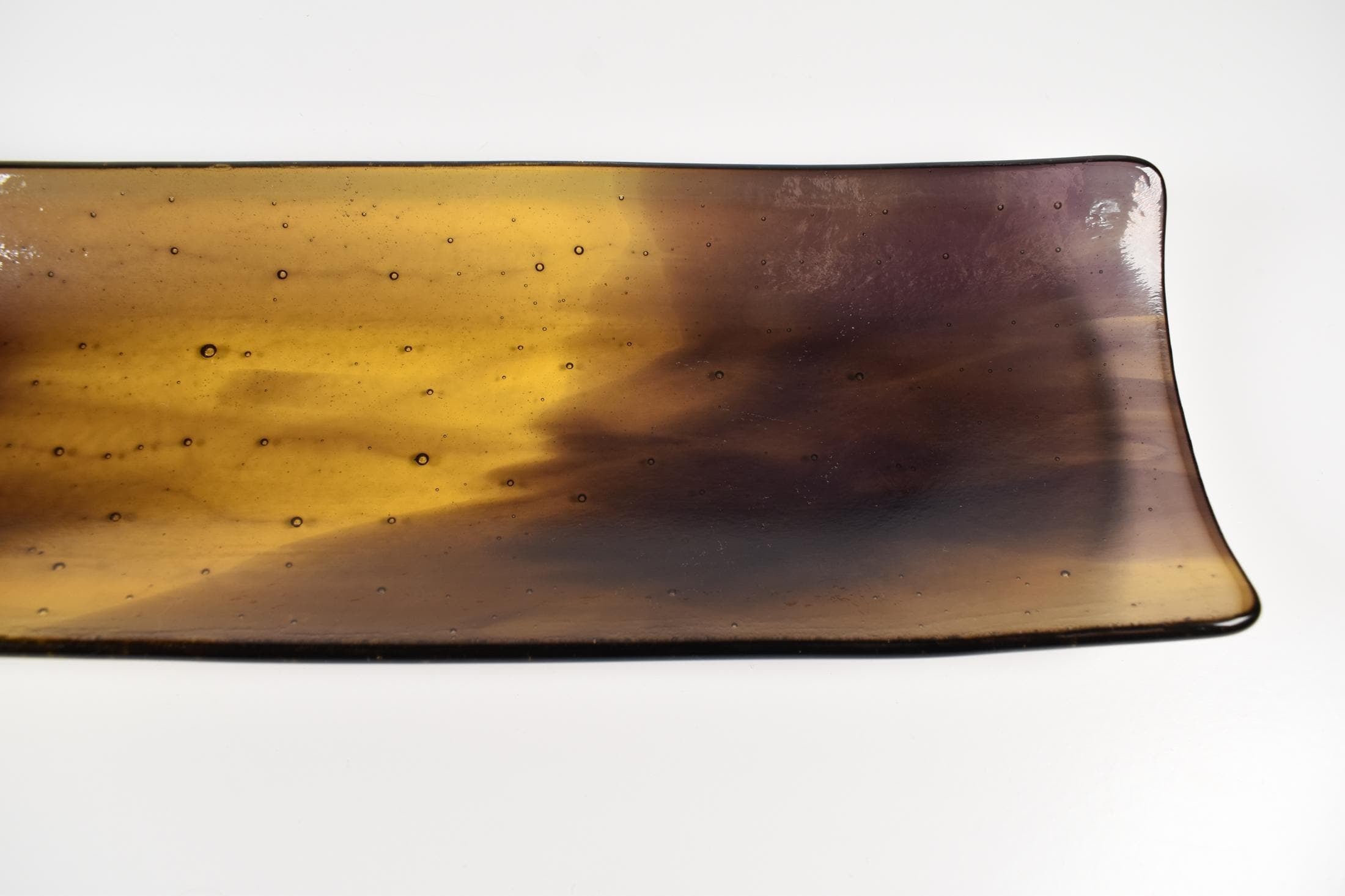Close-up of one corner of the tray showing the transition from amber to deep purple and small bubble texture in the glass.