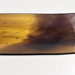 Close-up of one corner of the tray showing the transition from amber to deep purple and small bubble texture in the glass.