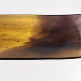 Close-up of one corner of the tray showing the transition from amber to deep purple and small bubble texture in the glass.
