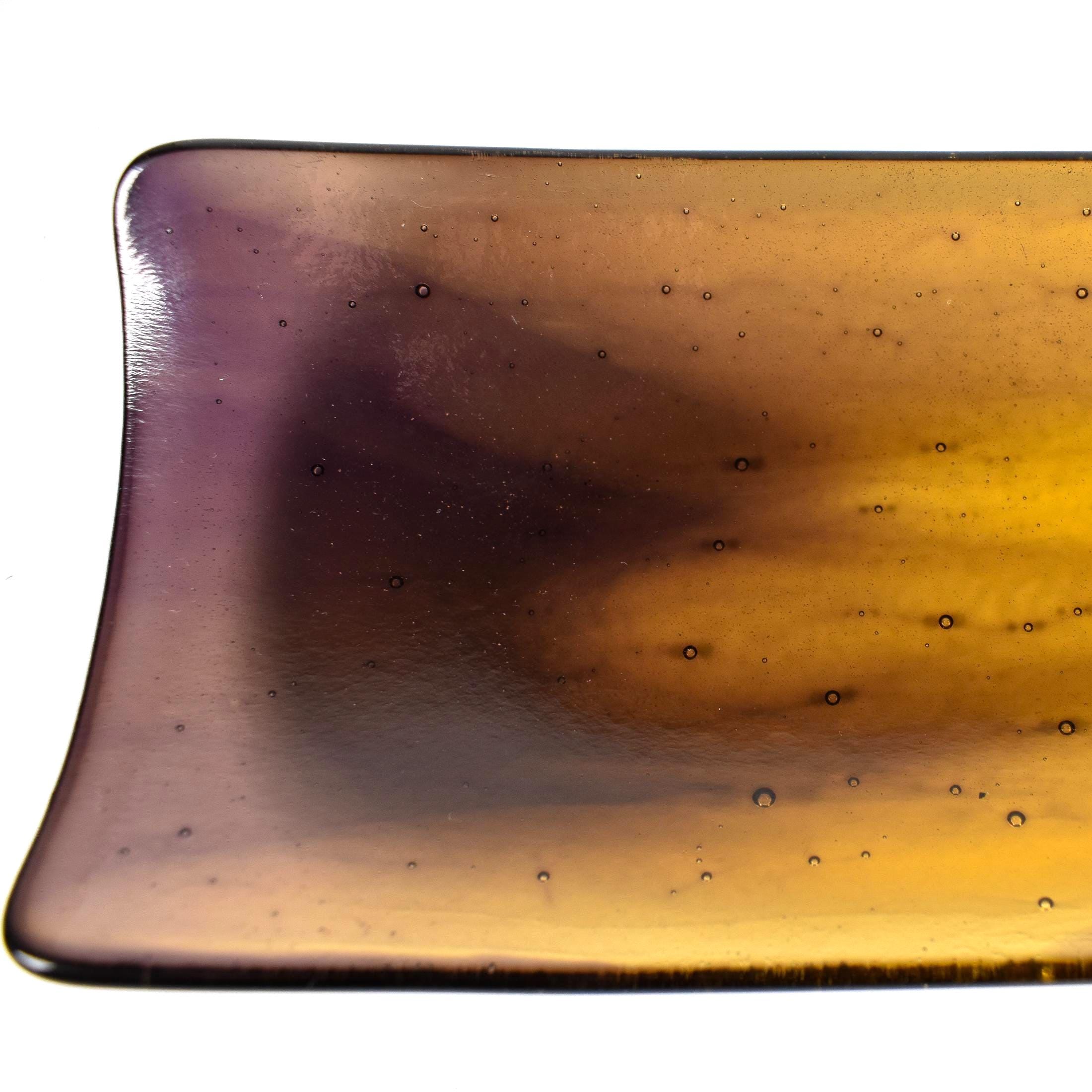 Close-up of one corner of the tray showing the transition from amber to deep purple and small bubble texture in the glass.