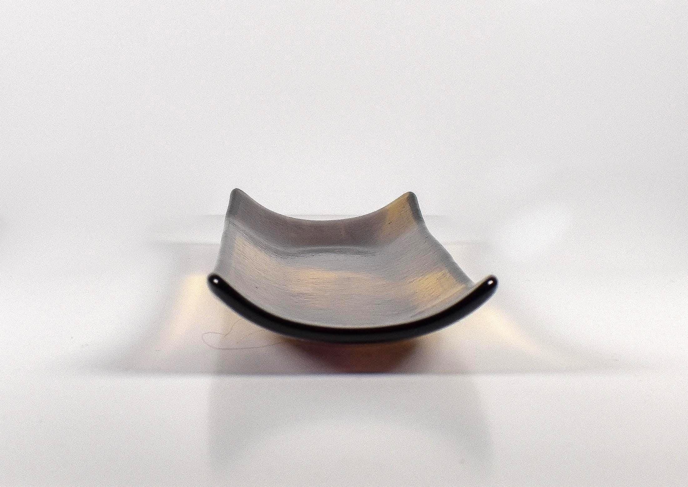 End view of the fused glass tray showing the curved channel shape and gently raised sides, with amber and deep purple glass.