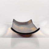 End view of the fused glass tray showing the curved channel shape and gently raised sides, with amber and deep purple glass.