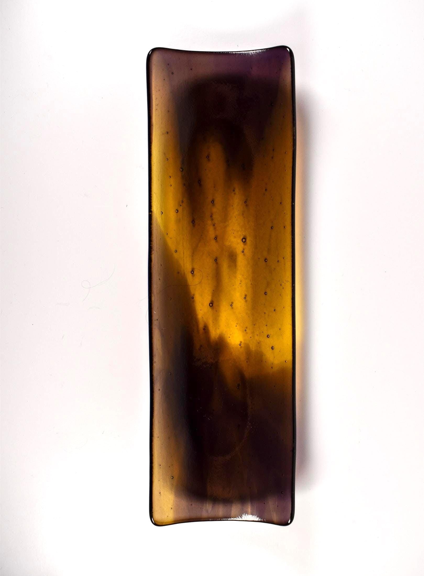 Top-down view of a 12” x 4” fused glass channel tray with transparent gold center and deep purple edges on white background.