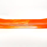 Orange and clear fused glass channel tray photographed from the side on a white background, with soft amber swirls in the center.