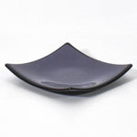 Square shaped, purple glass dish with black trim and slightly raised corners, on a white surface.