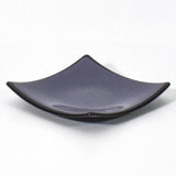 Square shaped, purple glass dish with black trim and slightly raised corners, on a white surface.