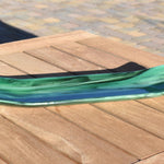 Green fused glass channel tray on an outdoor slatted wood table in sunlight, highlighting the glossy surface and color shifts.
