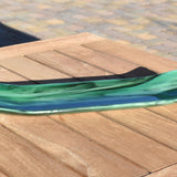 Green fused glass channel tray on an outdoor slatted wood table in sunlight, highlighting the glossy surface and color shifts.