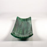 End view of a green kiln-formed glass channel dish showing the curved sides and trough shape on white.