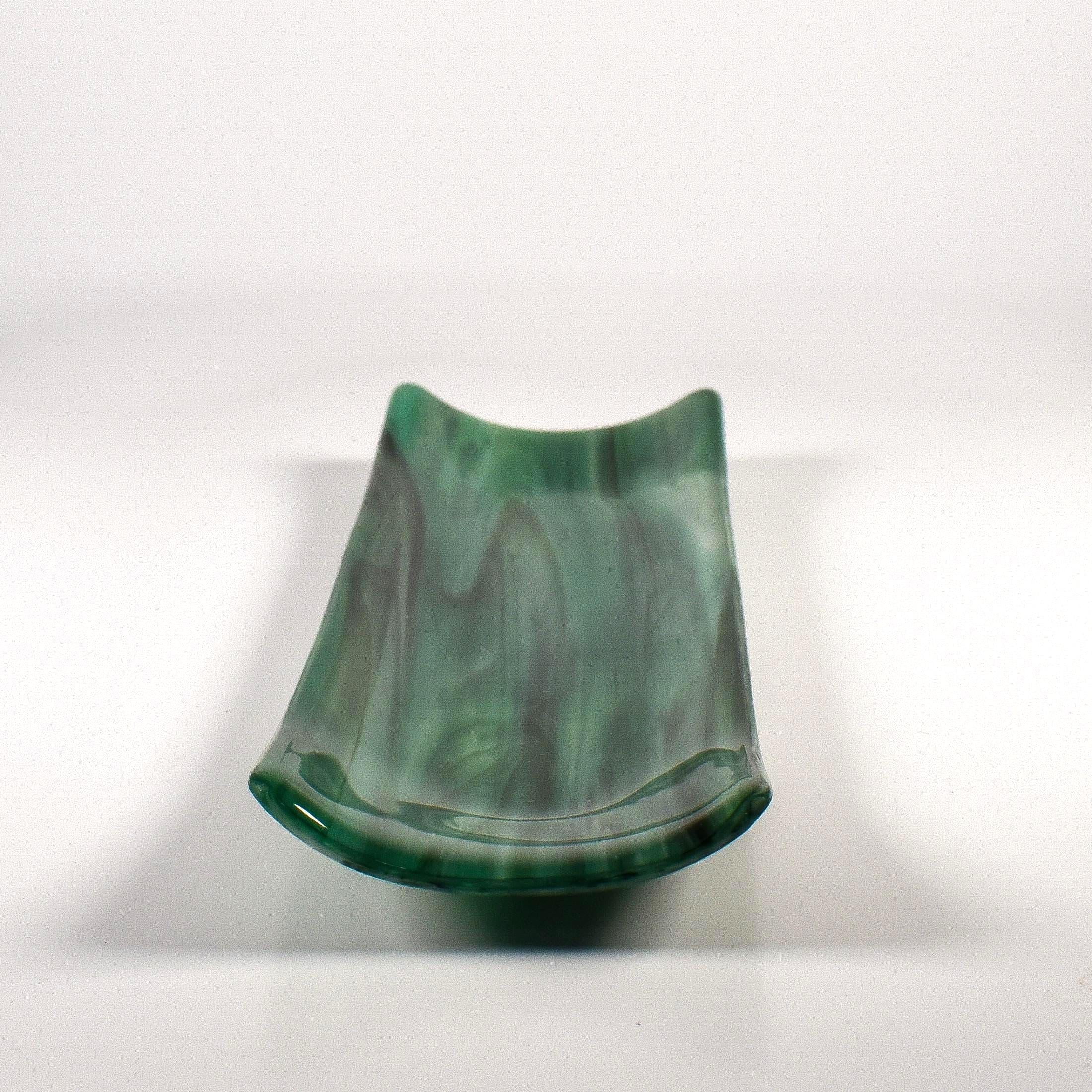 End view of a green kiln-formed glass channel dish showing the curved sides and trough shape on white.