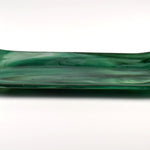 Side view of an emerald green fused glass channel tray with gently upturned ends on a white background.