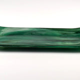 Side view of an emerald green fused glass channel tray with gently upturned ends on a white background.