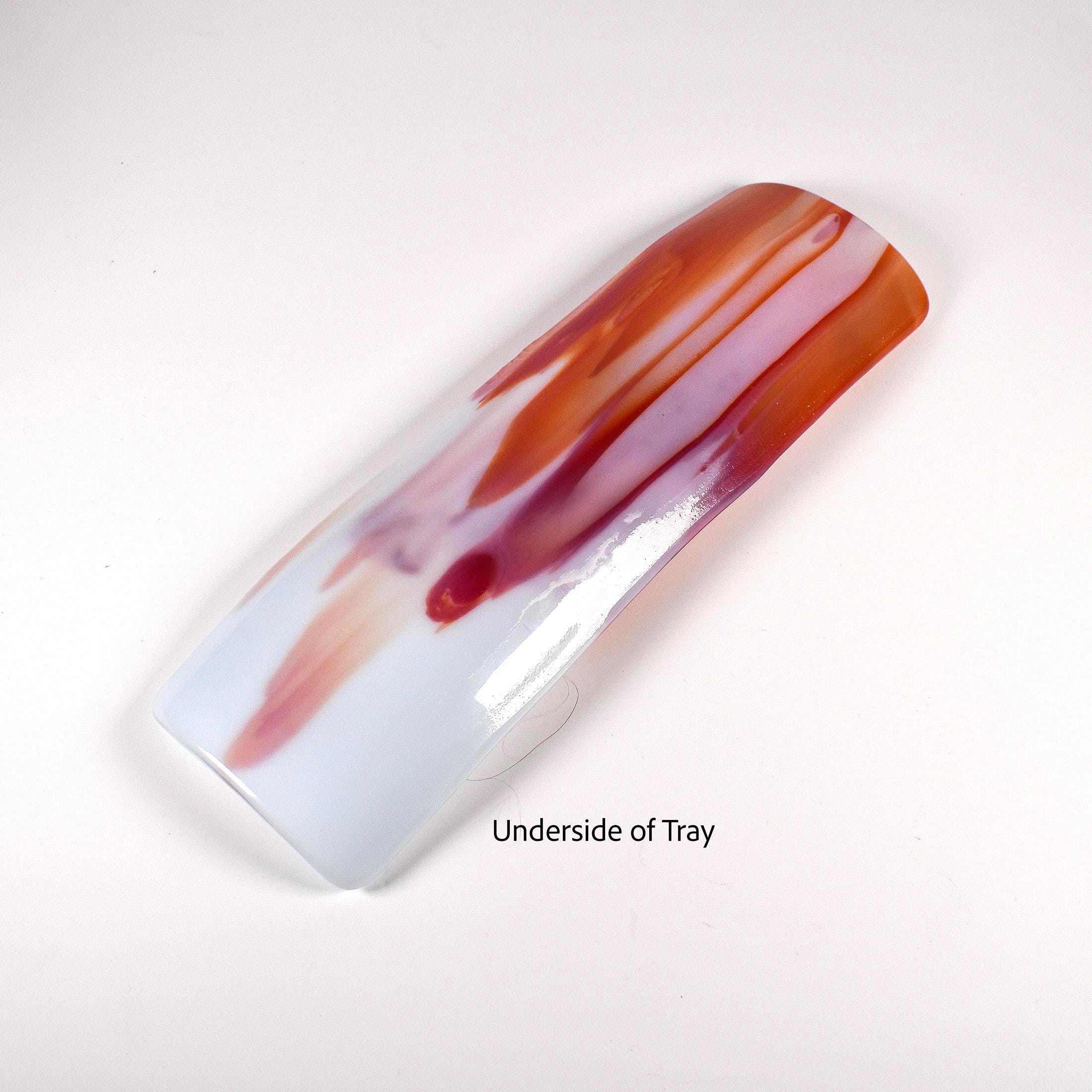 Underside of the tray on a white background, showing red and orange streaks beneath pale blue glass.