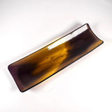 Top-down view of a 12” x 4” fused glass channel tray with transparent gold center and deep purple edges on white background.