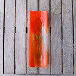 Orange and clear fused glass channel tray photographed from above a slatted wood table in natural light.