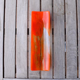Orange and clear fused glass channel tray photographed from above a slatted wood table in natural light.