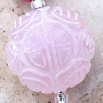 Close up view of large, puffed round, carved rose quartz stone bead.