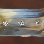 A rectangular glass dish with a marbled pattern in shades of brown, tan, and gray and gold. Three white flower-shaped embellishments are evenly spaced across the top. The dish is likely used for decorative purposes or as a small serving tray.