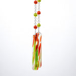 Two strings of glass beads hanging against white background, anchored by two pieces of green and orange fused glass.