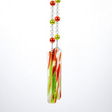 Two strings of glass beads hanging against white background, anchored by two pieces of green and orange fused glass.