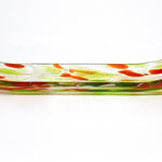 A rectangular glass dish with a curved design. The dish features a clear base with green and orange accents. The colors are distributed throughout the dish, creating a decorative pattern. The dish is likely used for serving or displaying items.